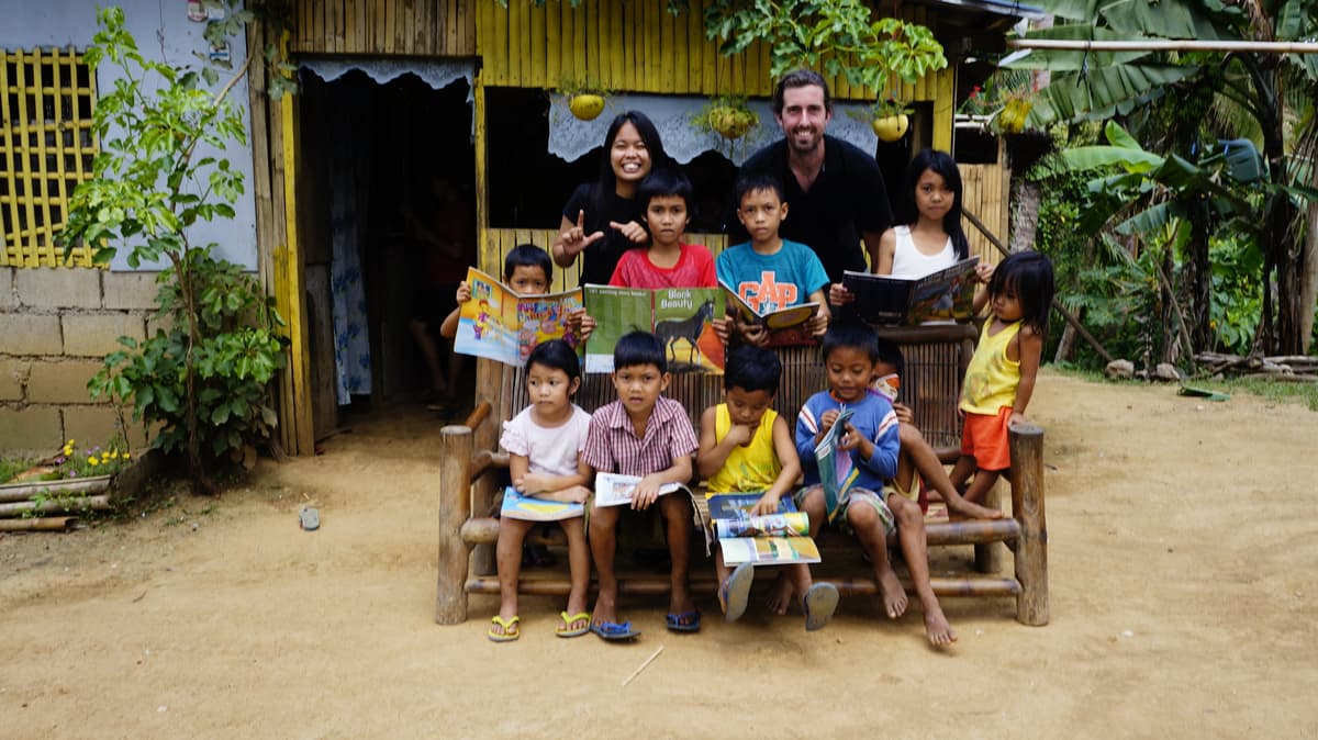 Jef van de Graaf and a fellow volunteer with kids holding books in Masbate, Philippines