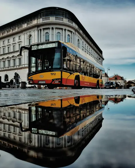 A city bus reflected in a puddle