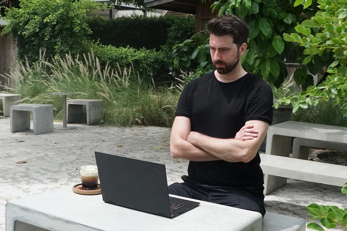 Jef van de Graaf at an outdoor table, arms crossed, looking at a website on his laptop